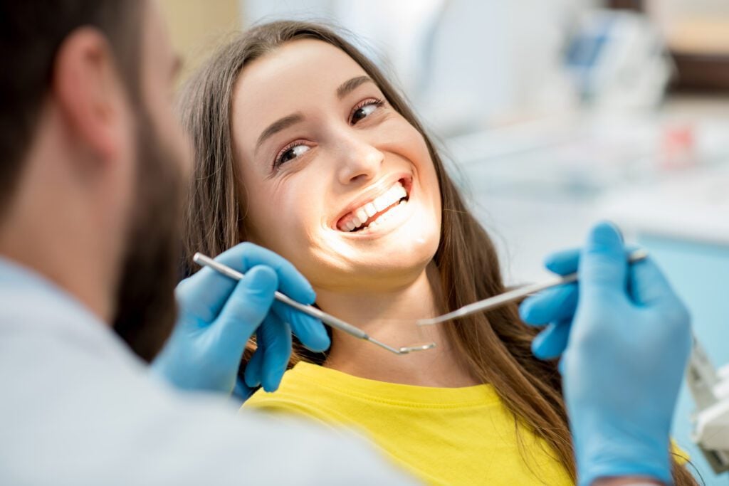 Portrait of a woman with toothy smile sitting during a cosmetic dentistry consultation.