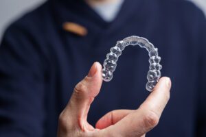 Man holding one transparent aligner. Invisalign orthodontics concept.