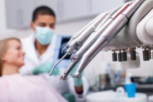 An image of dental exam instruments with a dentist in the background.