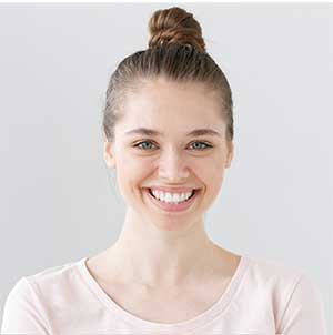 A young woman smiling happily with healthy teeth thanks to regular dental visits.