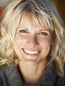 Blonde woman smiling at camera with white teeth.