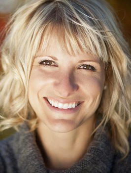 Blonde woman smiling at camera with white teeth.