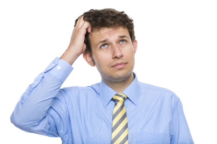 Man in a blue shirt and yellow tie scratching his head.