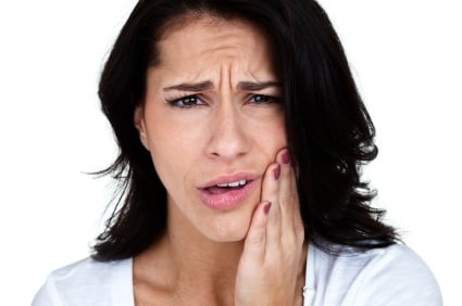 A young woman clutching her jaw in pain from untreated TMD in Lewisville.
